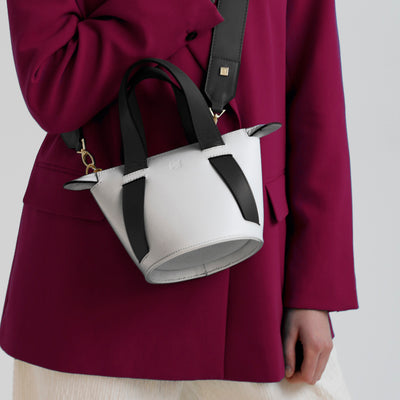 black and white leather bucket bag on dark pink blazer